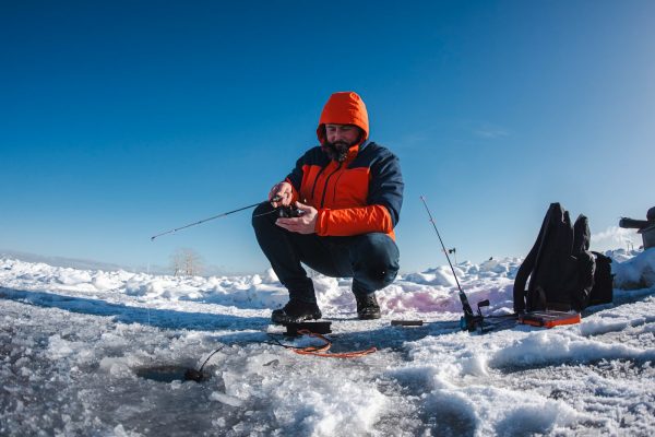 Man ice fishing on a frozen lake.